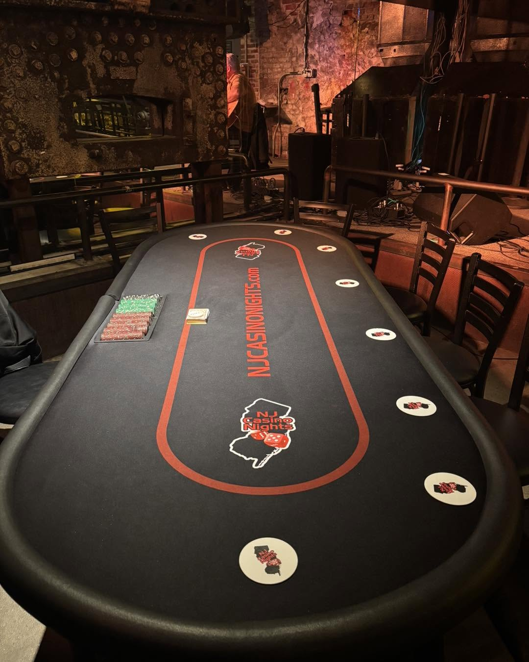 Branded NJ Casino Nights poker table at a rustic venue